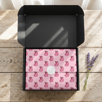 Open black SP Boutique gift box with pink tissue paper printed with cartoon ducks wearing sunglasses, folded and sealed with a round white sticker